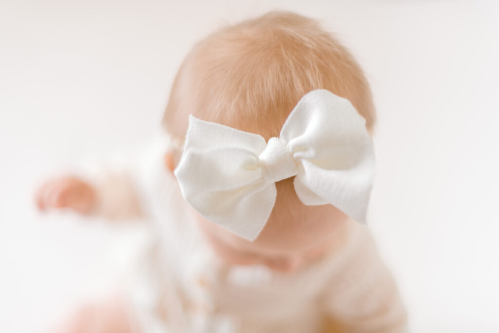 Up close photo of a white bow worn by a young six month old baby girl.