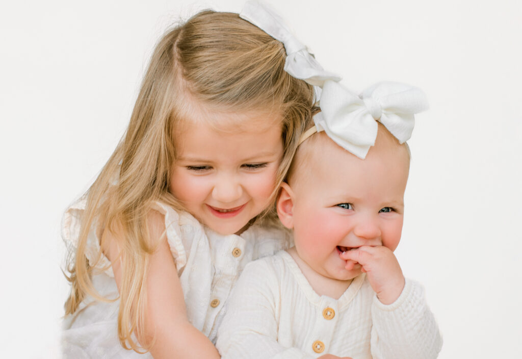 Sweet sisters hug and smile during a family photo session.
