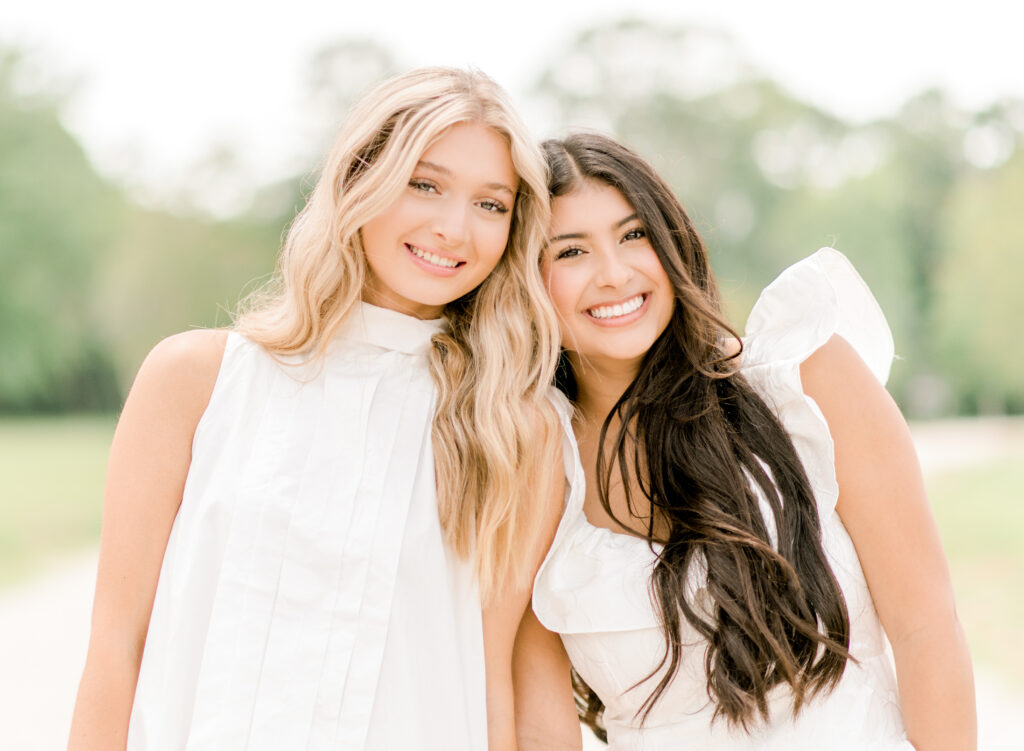 Blonde and brunette best girl friends squeeze in together during a senior graduation session.