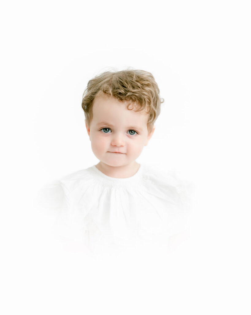 Young boy takes photo with Morgan Leigh Photography on all white backdrop.