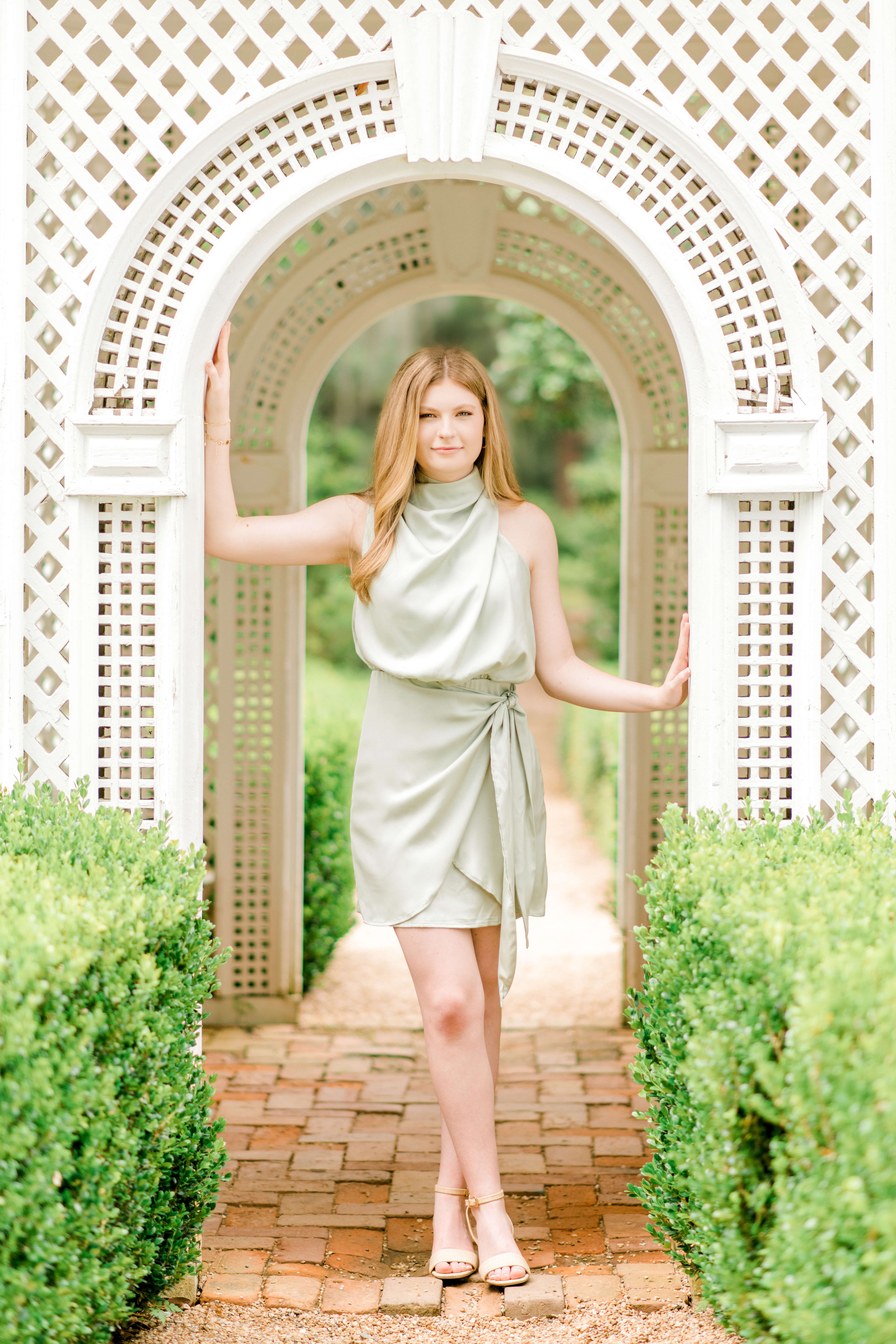 A gorgeous green dress accentuates the strawberry blonde hair as a senior poses in front of a terrace.