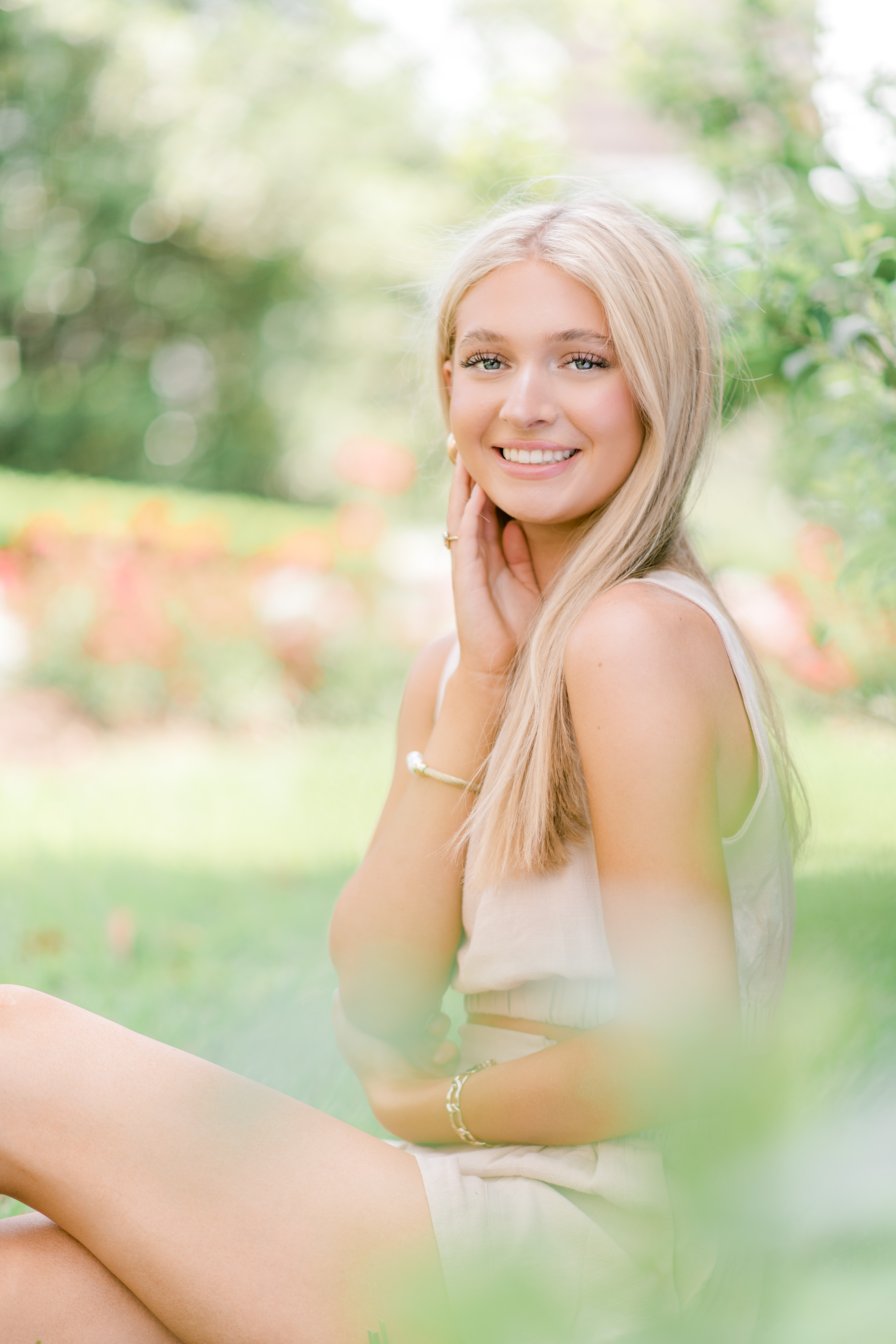 A beautiful girl sits in front of a field of bright flowers during a session by Morgan Leigh Photography.