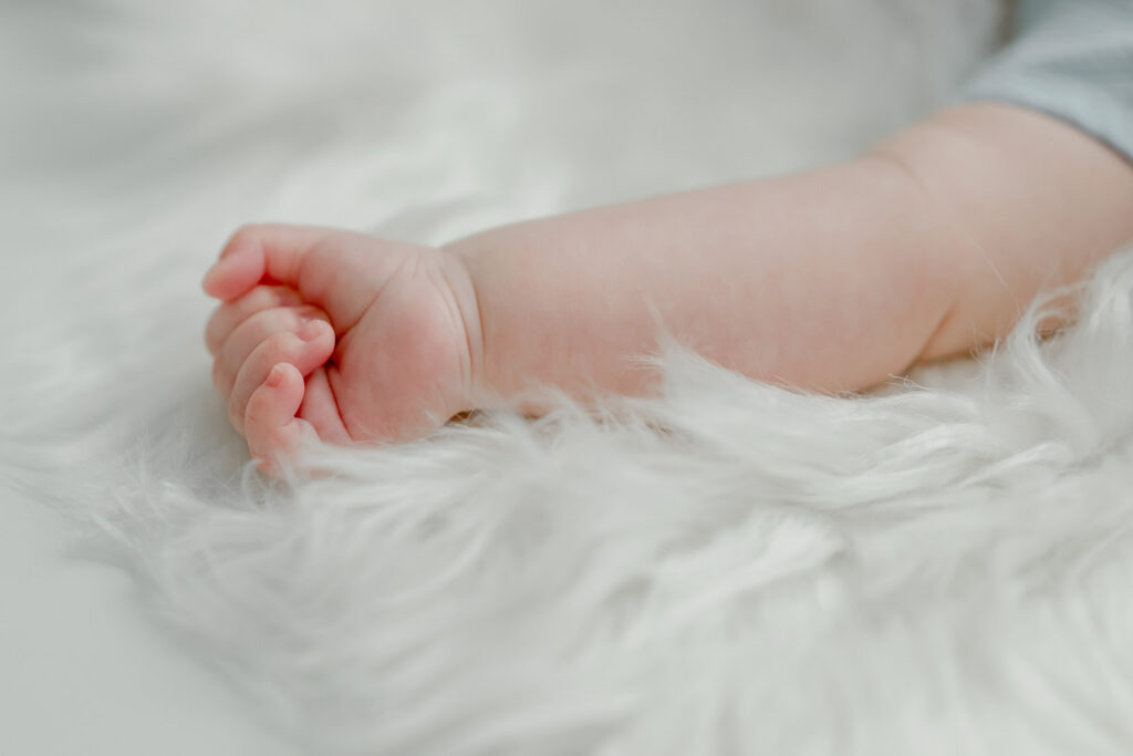 Up close photo of baby hand on all white backdrop.