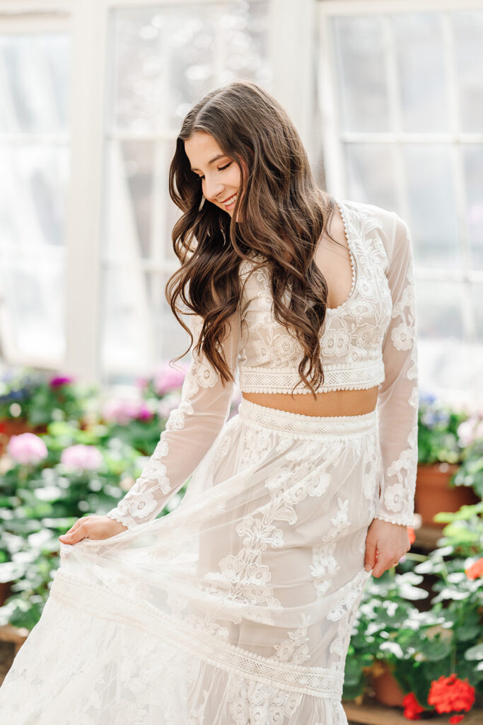 Senior in flowy skirt sways skirt in greenhouse full of flowers at Rosedown Plantation