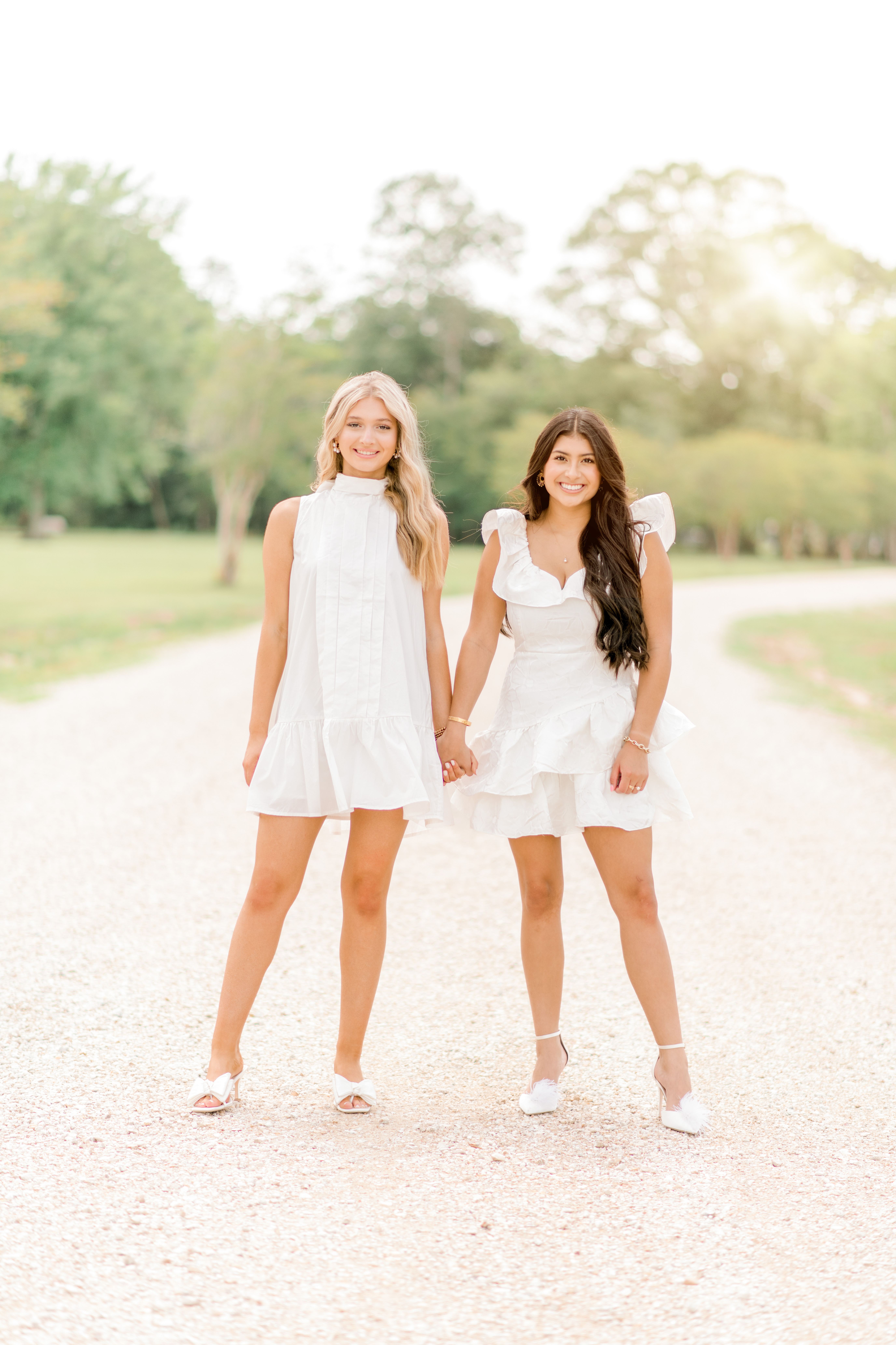 Senior friends stand in their homecoming dresses on a gravel path in Baton Rouge.