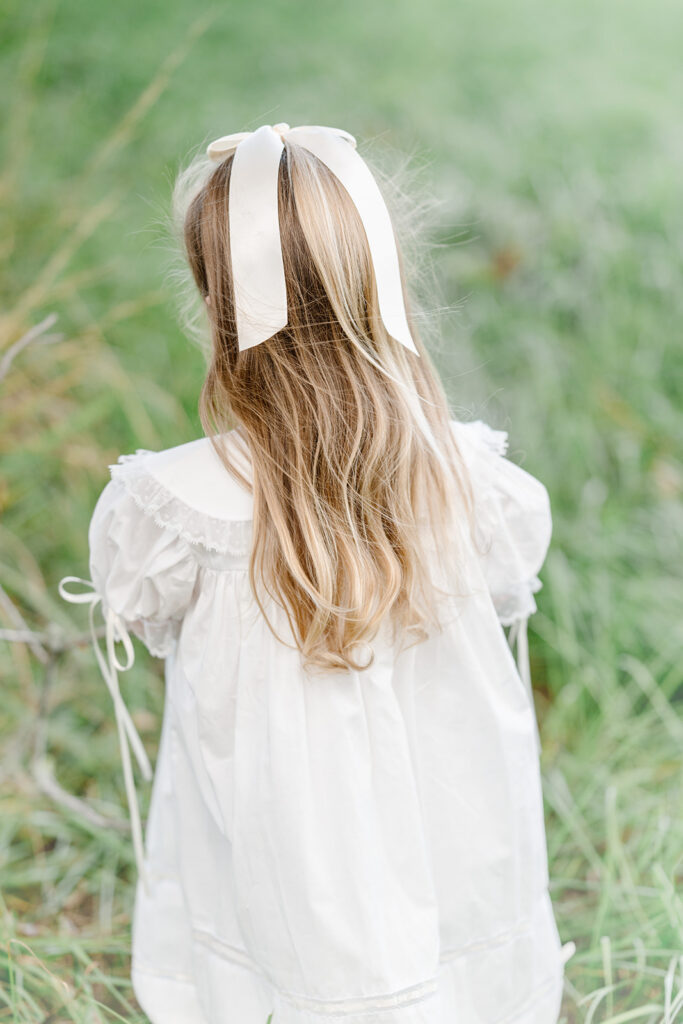 Young girl in white dress walks through a field in Baton Rouge.