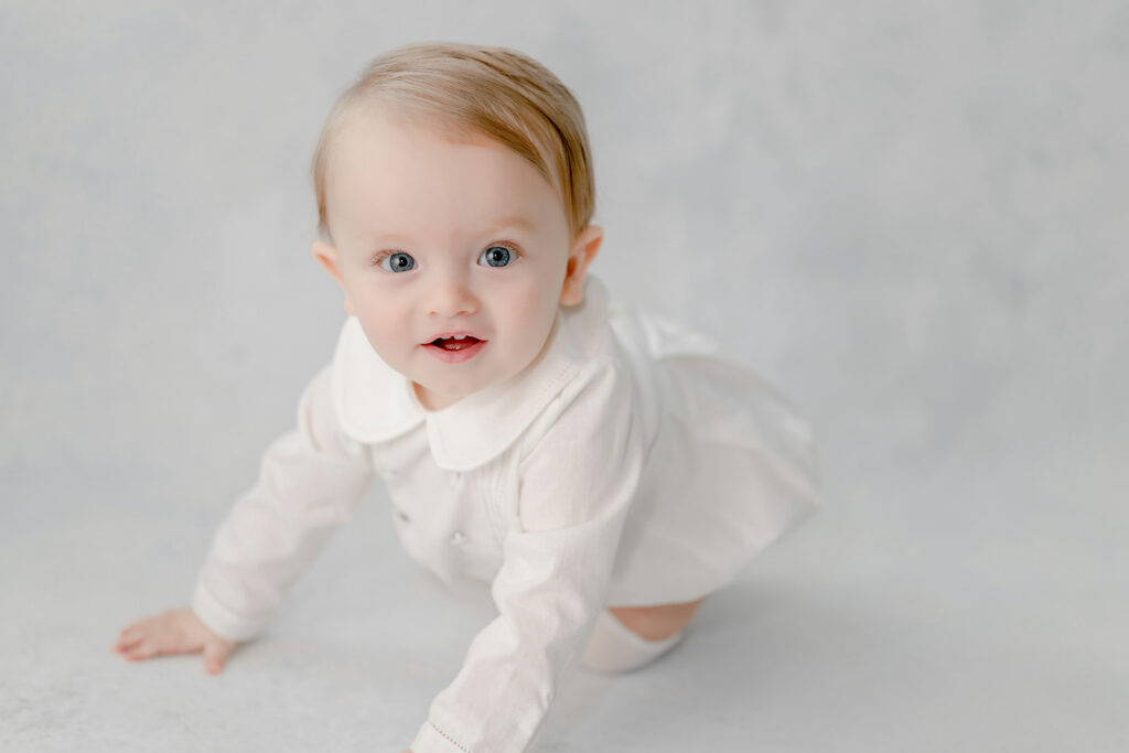 Baby in an outfit from children's boutique in Baton Rouge crawls during photo session with Morgan Leigh Photography.