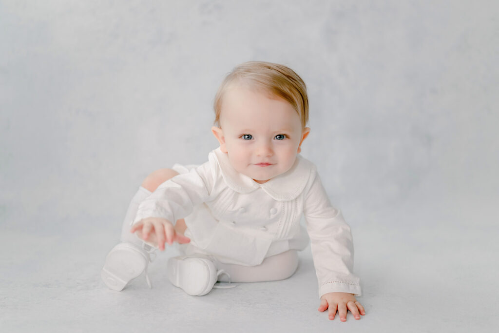 Baby smirks a mischievous grin as he crawls during an heirloom session.