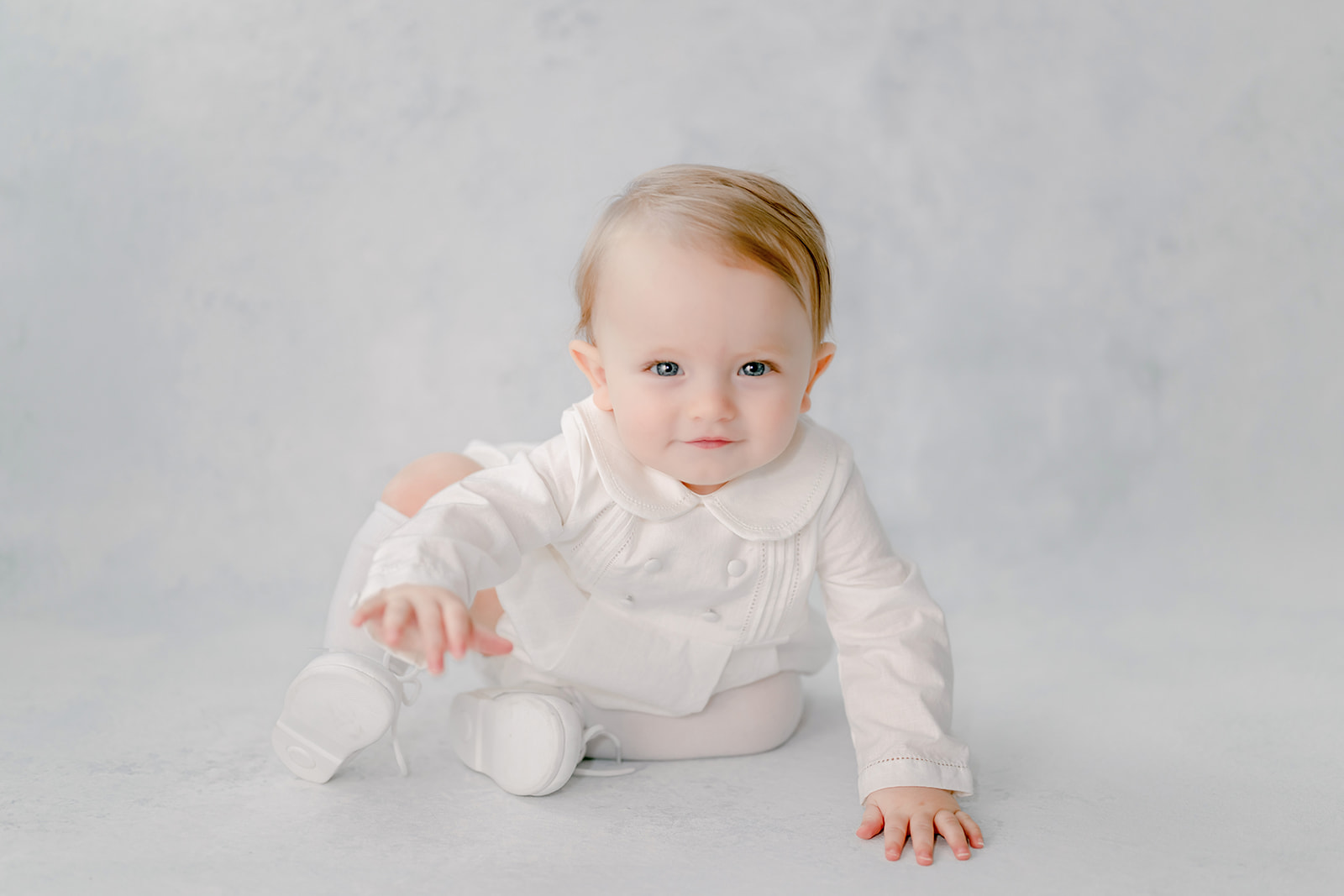 Baby smirks a mischievous grin as he crawls during an heirloom session.