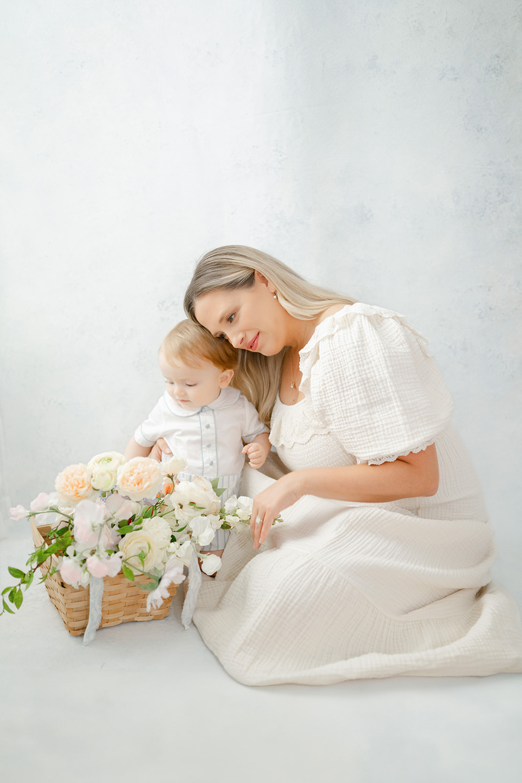 Morgan, owner of Morgan Leigh Photography, sits with her son and a basket of flowers for a photo session in her studio.